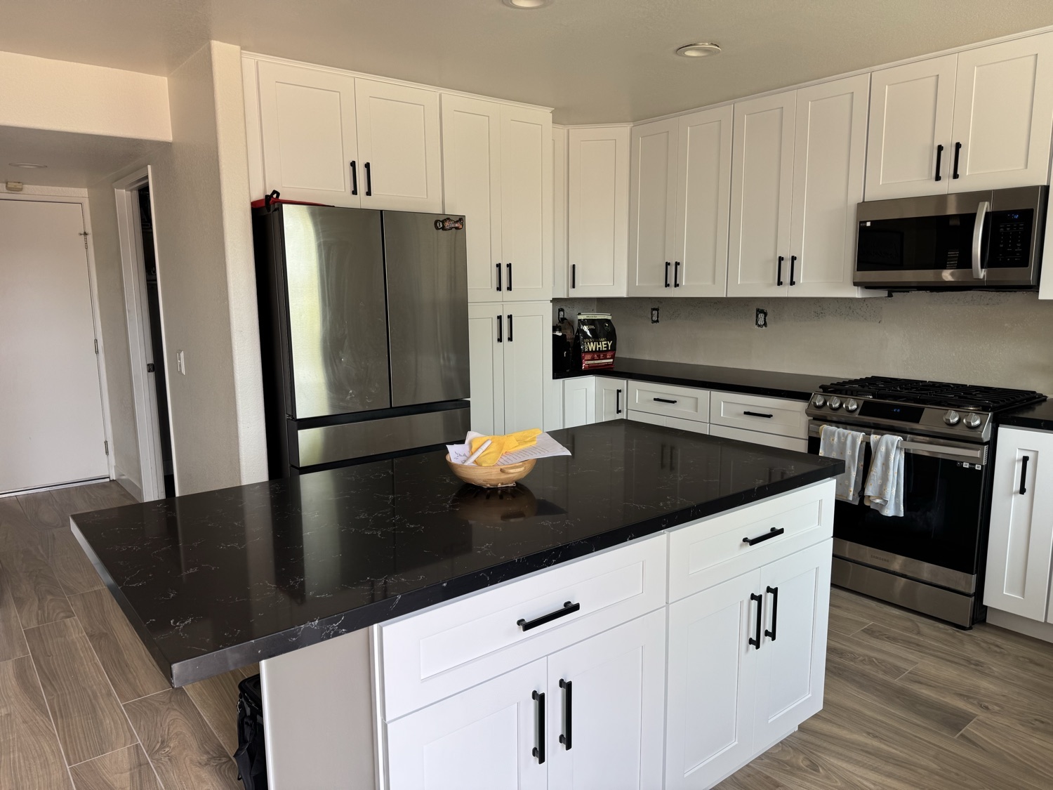 Bright modern kitchen remodel with white shaker cabinets and a black quartz island